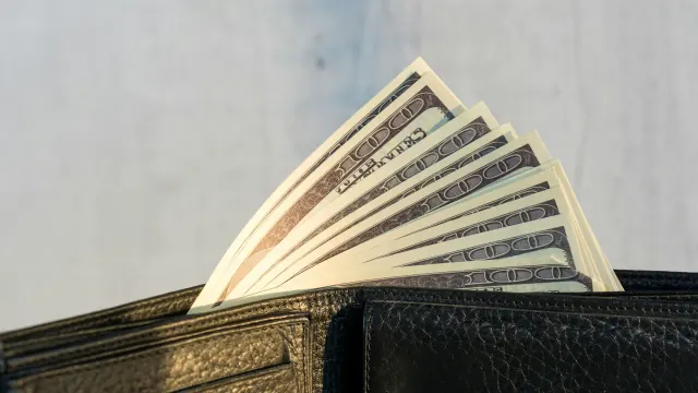 Cash tucked inside a wallet represents practical best ways to save money.