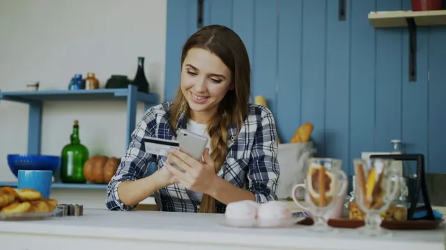 A woman reviews cash and a card at the table for how much fun money per month.