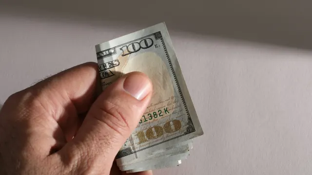 A hand holds a rolled bill, suggesting how to stash money discreetly.