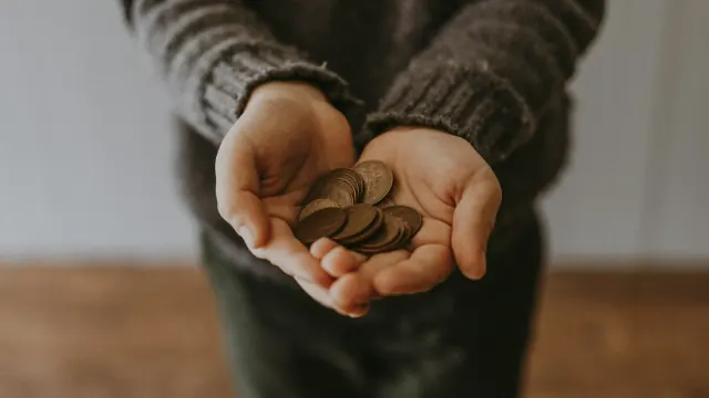 Hands hold loose coins, matching old fashioned money saving tips.