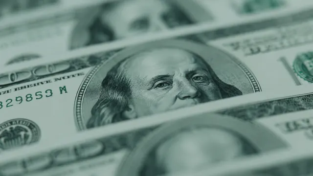 Close-up dollar bills spread across the frame for simple save on money habits.