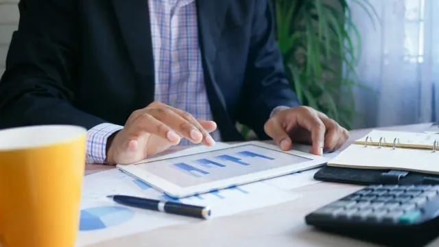 A planner, financial papers, and calculator on a desk for what is a savings plan.